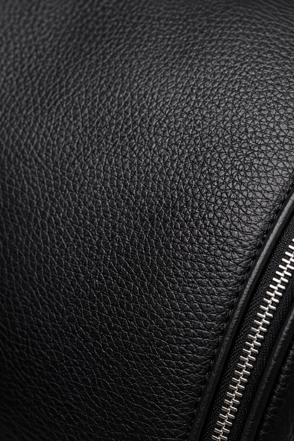Black full-grain leather texture and metal zipper detail on the C-01