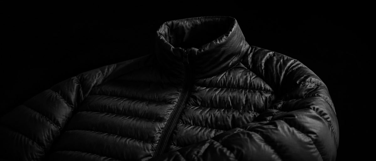Casaca de plumas J-01 en una composición editorial de la colección.