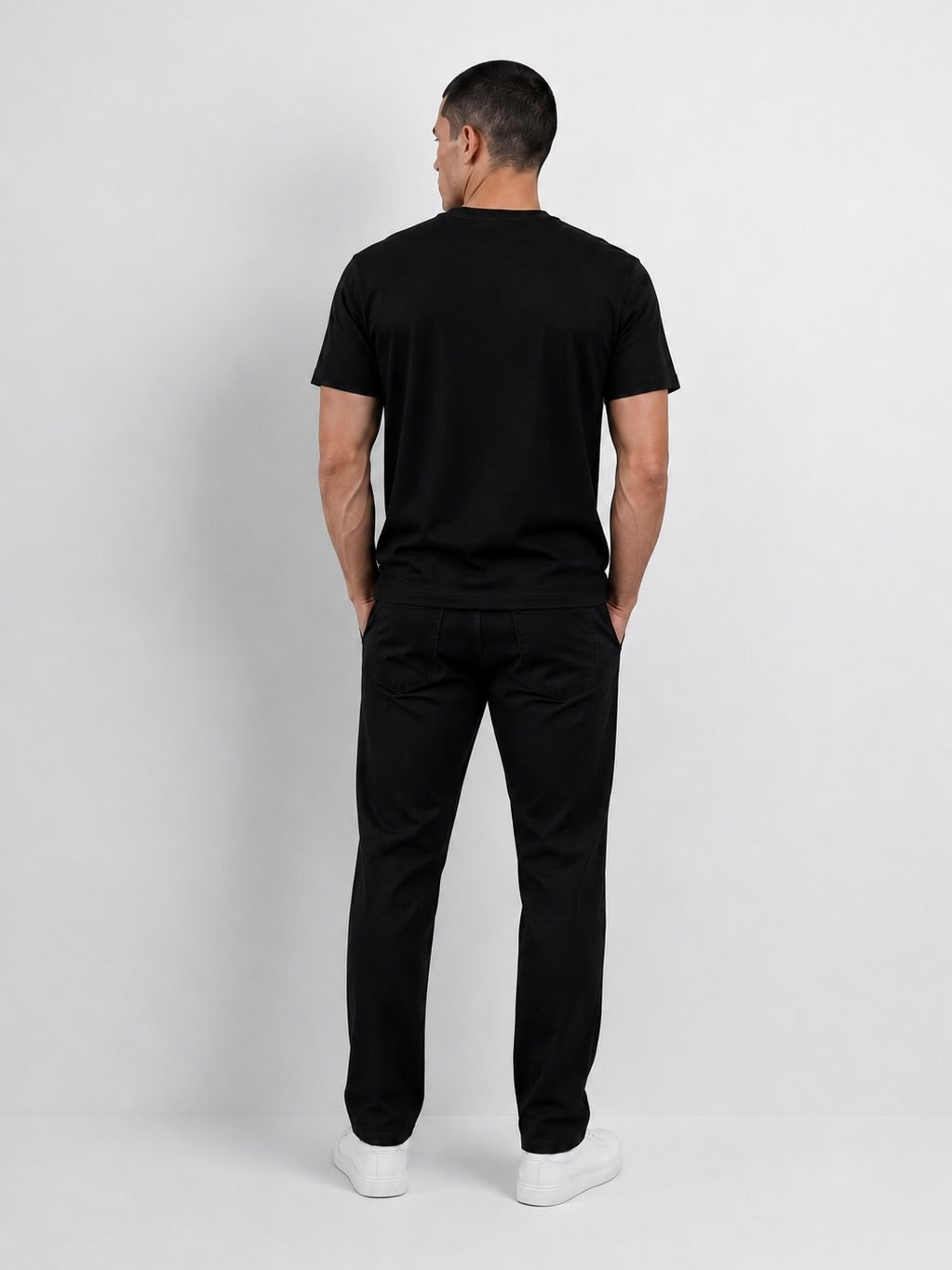 Modelo usando el polo negro T-01 Essential Pima, vista posterior.